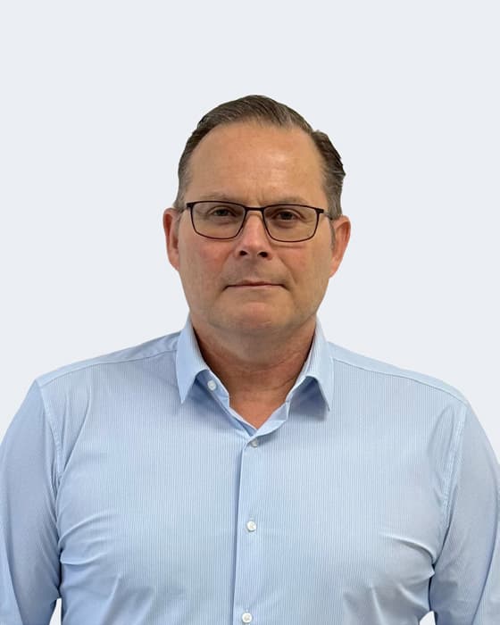 Professional headshot of a man wearing glasses and a light blue shirt against a plain white background.