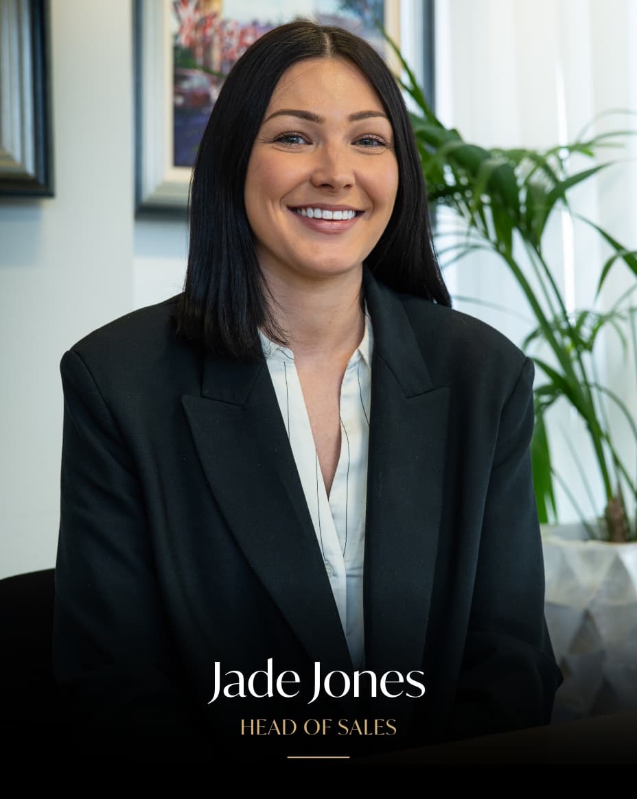 Professional headshot of Jade Jones, Head of Sales, wearing a black blazer and white shirt in an office setting with a potted plant in the background.