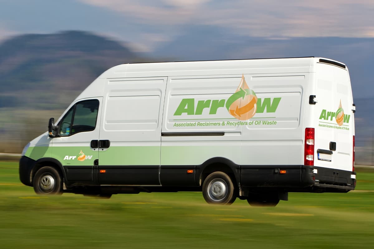 White and green branded van belonging to Arrow, Associated Reclaimers & Recyclers of Oil Waste, driving through a rural landscape.