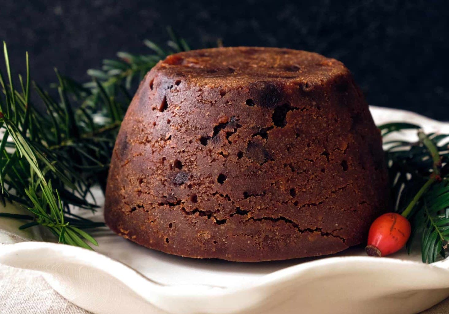 Christmas pudding on a white cloth with winter foliage